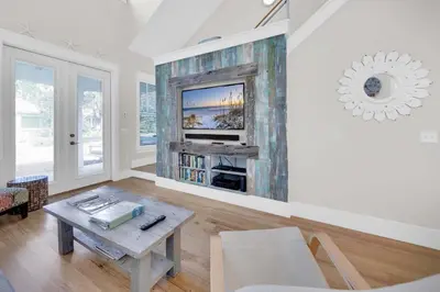 a living room with a table and a tv at Claire N' Bea by the Sea in Santa Rosa Beach