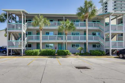 a large apartment building with palm trees in a parking lot at Panama City Beach Condo with Pool and Beach Access! in Panama City Beach