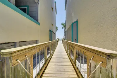 a wooden walkway leading down to a building at Panama City Beach Condo with Pool and Beach Access! in Panama City Beach