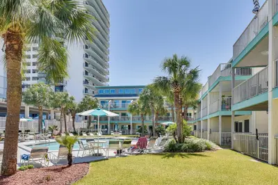 a resort with a pool and palm trees and a hotel at Panama City Beach Condo with Pool and Beach Access! in Panama City Beach