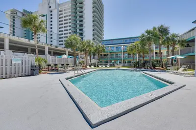 a swimming pool with palm trees and a building at Panama City Beach Condo with Pool and Beach Access! in Panama City Beach