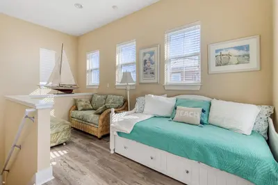 a bedroom with a bed and a chair and windows at Casa Del Mar in Panama City Beach