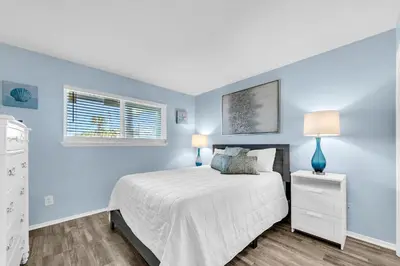 a bedroom with a white bed and blue walls at Nautical Watch E-3 in Panama City Beach
