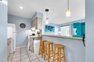 a kitchen with blue cabinets and two bar stools at Nautical Watch E-3 in Panama City Beach