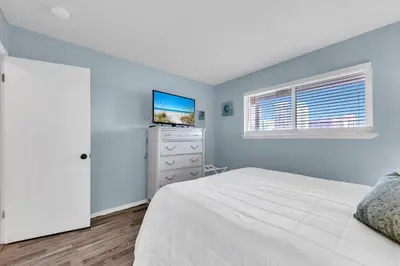 a bedroom with a white bed and a tv at Nautical Watch E-3 in Panama City Beach