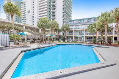 a swimming pool with palm trees and a building at Nautical Watch E-3 in Panama City Beach