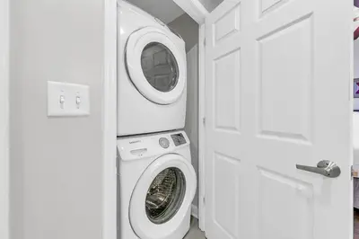 a washer and dryer in a white room with a door at Sterling Reef 1504 in Panama City Beach