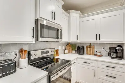 a kitchen with white cabinets and stainless steel appliances at Chic Panama City Beach Home, Walk to Laguna Beach! in Panama City Beach