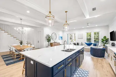 a kitchen and living room with blue cabinets and a table at Southern Grove in Santa Rosa Beach