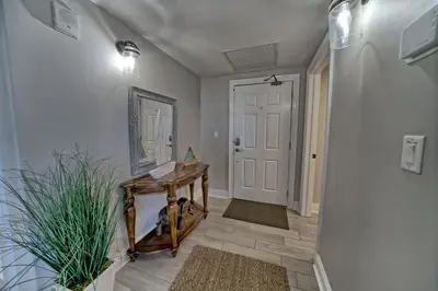a hallway with a wooden table and a white door at Modern Oceanfront Retreat, Spacious Balcony - 0207 condo in Panama City Beach