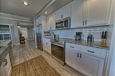 a kitchen with white cabinets and a stove top oven at Modern Oceanfront Retreat, Spacious Balcony - 0207 condo in Panama City Beach