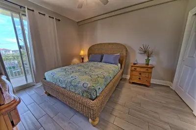 a bedroom with a wicker bed and a night stand at Modern Oceanfront Retreat, Spacious Balcony - 0207 condo in Panama City Beach