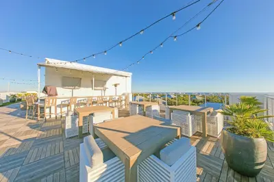a deck with tables and chairs on the beach at The Pointe 1-134 in Inlet Beach