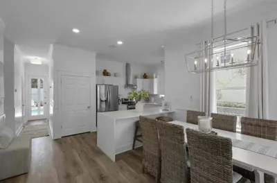 a white kitchen with a table and chairs and a counter at Hattie's Hideawy at Seacrest in Santa Rosa Beach