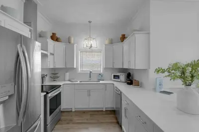a white kitchen with white cabinets and a refrigerator at Hattie's Hideawy at Seacrest in Santa Rosa Beach