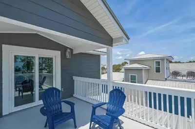 two blue chairs sitting on the front porch of a house at Hattie's Hideawy at Seacrest in Santa Rosa Beach