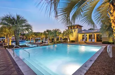 a large swimming pool with palm trees and a house at Endless Summer Nights at Seacrest in Inlet Beach