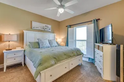 a bedroom with a bed and a flat screen tv at Walk to Shore Panama City Beach Condo with Pool in Panama City Beach