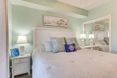 a bedroom with a bed with two lamps and a mirror at Walk to Shore Panama City Beach Condo with Pool in Panama City Beach
