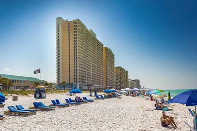 a beach with chairs and umbrellas and people on it at Walk to Shore Panama City Beach Condo with Pool in Panama City Beach