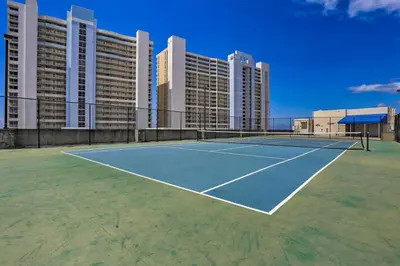 a tennis court in front of a large building at Walk to Shore Panama City Beach Condo with Pool in Panama City Beach