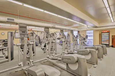 a gym with rows of treadmills and machines at Walk to Shore Panama City Beach Condo with Pool in Panama City Beach