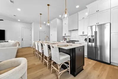a kitchen with white cabinets and a large kitchen island with bar chairs at Shimmy By The Sea by 30A Escapes in Panama City Beach