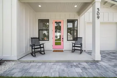 two chairs on a porch with a pink door at Shimmy By The Sea by 30A Escapes in Panama City Beach
