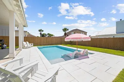 a swimming pool with a pink umbrella and white chairs at Shimmy By The Sea by 30A Escapes in Panama City Beach