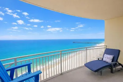 a balcony with a blue chair and the ocean at Ocean Blue at 1805 Aqua in Panama City Beach