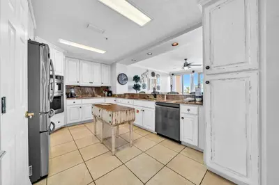 a kitchen with white cabinets and a table in it at Hidden Dunes 203 in Panama City Beach