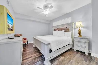 a bedroom with a white bed and a ceiling fan at Hidden Dunes 203 in Panama City Beach