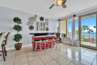 a kitchen with a bar with stools and a balcony at Hidden Dunes 203 in Panama City Beach
