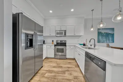 a kitchen with white cabinets and stainless steel appliances at Newly renovated overlooking the Seacrest Village Pool and Beach access in Rosemary Beach