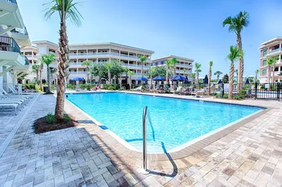 a swimming pool at a resort with palm trees and buildings at Newly renovated overlooking the Seacrest Village Pool and Beach access in Rosemary Beach