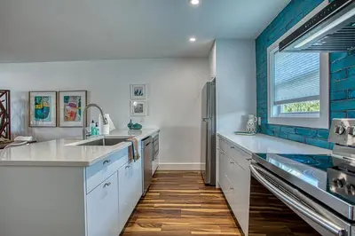 a kitchen with white cabinets and a blue wall at Gulf Views! Only 30 Seconds to the beach Modern Amenities Meets Vintage Charm in Inlet Beach