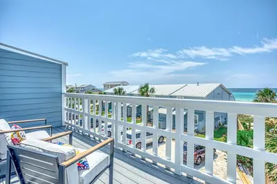 a balcony with two chairs and the ocean at Gulf Views! Only 30 Seconds to the beach Modern Amenities Meets Vintage Charm in Inlet Beach
