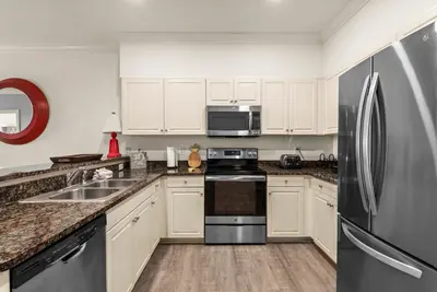 a kitchen with white cabinets and a stainless steel refrigerator at Newly Renovated Village Condo! Easy Beach & Pool Access! in Rosemary Beach