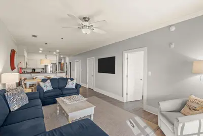 a living room with blue couches and a tv at Newly Renovated Village Condo! Easy Beach & Pool Access! in Rosemary Beach