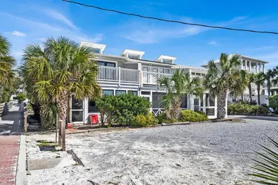 a large white building with palm trees in front of it at Gulf Front, Stunning Views! Newly Renovated! Dolphin Watch #1 in Seacrest
