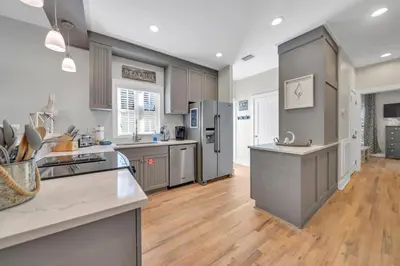 a large kitchen with stainless steel appliances and wooden floors at Magnolia Cottages Seacrest Flirty Flamingo - Pet Friendly Resort Pool & Beach Access! in Seacrest