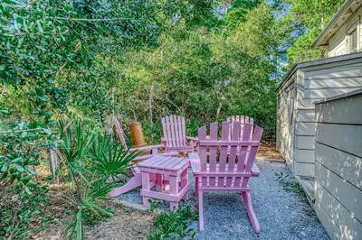 two chairs and a table in a yard at Magnolia Cottages Seacrest Flirty Flamingo - Pet Friendly Resort Pool & Beach Access! in Seacrest