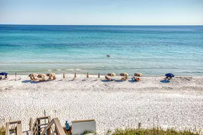 a sandy beach with umbrellas and the ocean at Magnolia Cottages Seacrest Flirty Flamingo - Pet Friendly Resort Pool & Beach Access! in Seacrest