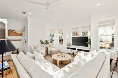 a living room with white furniture and a flat screen tv at Katmanblu - Over 45 Five Star Reviews! Custom-Built! Easy Beach & Pool Access! in Rosemary Beach