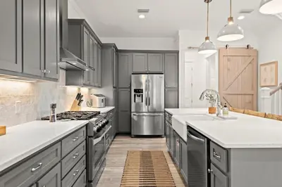a kitchen with gray cabinets and stainless steel appliances at Katmanblu - Over 45 Five Star Reviews! Custom-Built! Easy Beach & Pool Access! in Rosemary Beach
