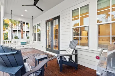 a porch with two chairs and a table at Katmanblu - Over 45 Five Star Reviews! Custom-Built! Easy Beach & Pool Access! in Rosemary Beach
