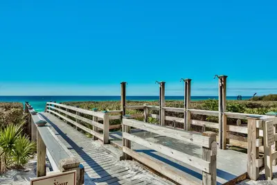 a wooden boardwalk to the beach with the ocean in the background at Village of South Walton Studio Ground Floor Easy Beach & Pool Access! in Rosemary Beach