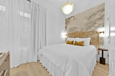 a white bedroom with a white bed and a chandelier at Village of South Walton Studio Ground Floor Easy Beach & Pool Access! in Rosemary Beach