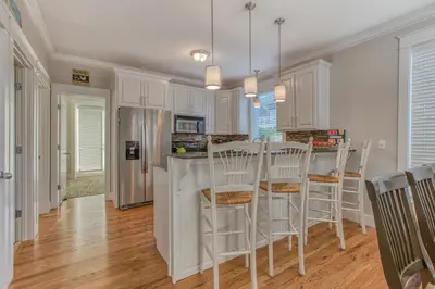 a kitchen with white cabinets and a island with bar stools at 50 yards to the Seacrest lagoon Pool, Walking distance to the beach! in Rosemary Beach