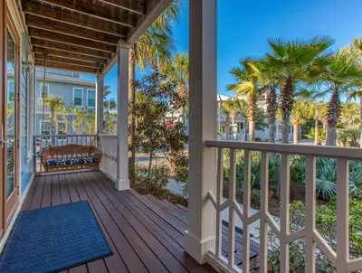 a porch with palm trees and a blue rug at 50 yards to the Seacrest lagoon Pool, Walking distance to the beach! in Rosemary Beach